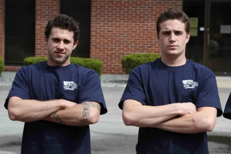 Two Expert Moving crew members in navy shirts, arms crossed