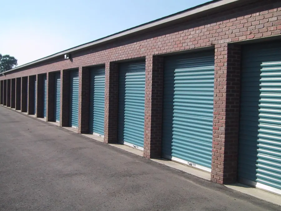 Row of brick storage units with teal roll-up doors